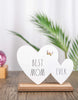 Load image into Gallery viewer, Lifestyle picture of the &quot;Best Mom Ever&quot; sign. The plaque is placed in a face-forward position, standing on a wooden table. The background is blurred; however, a palm plant is distinguishable on the right side, a snow globe with a wooden base and a purple-colored glass on the left side, and a white curtain is visible in the farthest part.
