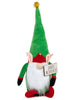Load image into Gallery viewer, Frontal view of the Rae Dunn Christmas-themed gnome. From this angle, all its key features are clearly visible: The wooden sign with the term &quot;Santa&#39;s Workshop&quot;, the green jacket, its green pointy hat, and the red-colored curled-toe shoes. The background of the picture is white.
