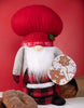 Load image into Gallery viewer, Lifestyle picture of the chef gnome featuring a Christmas theme. It is placed on a table with a white tablecloth, surrounded by breads in the front and back.
