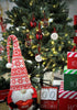 Load image into Gallery viewer, Second lifestyle picture of the Christmas ornaments with words on it. They are hanging on a Christmas tree with lighting bulbs on it. In front of the tree, there&#39;s a red and white Christmas gnome that holds a red decorative heart. There are also three decorative red, white, and green Christmas boxes on the right side, one above the other. Next to the boxes, there&#39;s a decorative calendar with the term &quot;Days &#39;Till Christmas&quot; on it.
