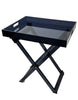 Load image into Gallery viewer, Side-angle view of the black smoke acrylic table, shown from a right-tilted perspective. All its features are visible: the foldable legs, the rectangular shape with raised edges, the sleek black translucent surface, and the handles on the shorter sides. The background of the picture is white.
