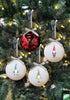 Load image into Gallery viewer, Lifestyle picture of the set of 4 gnome tree ornaments. They are hanging on a Christmas tree with lighting bulbs. The light is reflected on the ornaments, giving it a shining effect.
