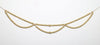 Load image into Gallery viewer, Front view of the interwoven garland with gold-colored glossy beads. In this view, all its features are visible: the two strings crossing each other to form three hanging sections on the lower beaded string, the gold-colored beads with their glossy finish, and the khaki-colored string cord. The background of the picture is gray.
