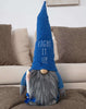 Load image into Gallery viewer, Lifestyle picture of the Hanukkah gnome. It is placed in a frontal position, standing on a brown furniture.
