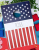 Load image into Gallery viewer, Lifestyle picture of the patriotic-themed board. It is placed at a left-tilted angle, resting on a surface divided into white, red, and blue sections. To its left, four blue bean bags are visible, while four red bean bags can be seen to its right.
