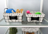 Load image into Gallery viewer, Lifestyle picture of the baskets, captured from a frontal angle and placed on a clear glass tabletop. A gray wall can be seen in the background. The basket labeled “Toys” is on the left and contains three brown-colored dog bone toys, along with a small blue vacuum for pet hair. On the right, the basket labeled “Stuff” is placed, showing a pink dog bone toy and a green ball inside. The picture serves as an example of the types of items that can be placed in the baskets.
