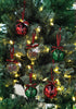 Load image into Gallery viewer, Lifestyle picture of the set of Rae Dunn Christmas ornaments. They are hanging on a Christmas tree with lighting bulbs on it. The light is reflected on the ornaments, giving it a shining effect.
