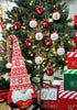 Load image into Gallery viewer, Lifestyle picture showcasing the red and white Christmas tree balls. They are hanging on a Christmas tree with lighting bulbs on it. In front of the tree, there&#39;s a red and white Christmas gnome that holds a red decorative heart. There are also three decorative red, white, and green Christmas boxes on the right side, one above the other. Next to the boxes, there&#39;s a decorative calendar with the term &quot;Days &#39;Till Christmas&quot; on it.
