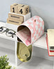Load image into Gallery viewer, Lifestyle picture of the mailbox. It is positioned on the edge of a white table from a diagonal angle. The mailbox door is open, revealing a pink-colored envelope with illustrations of hearts. On the left, a pair of glasses can be seen, while two books, one above the other, decorate the right side of the table. The wall behind is gray, and below the table, there&#39;s an empty space.
